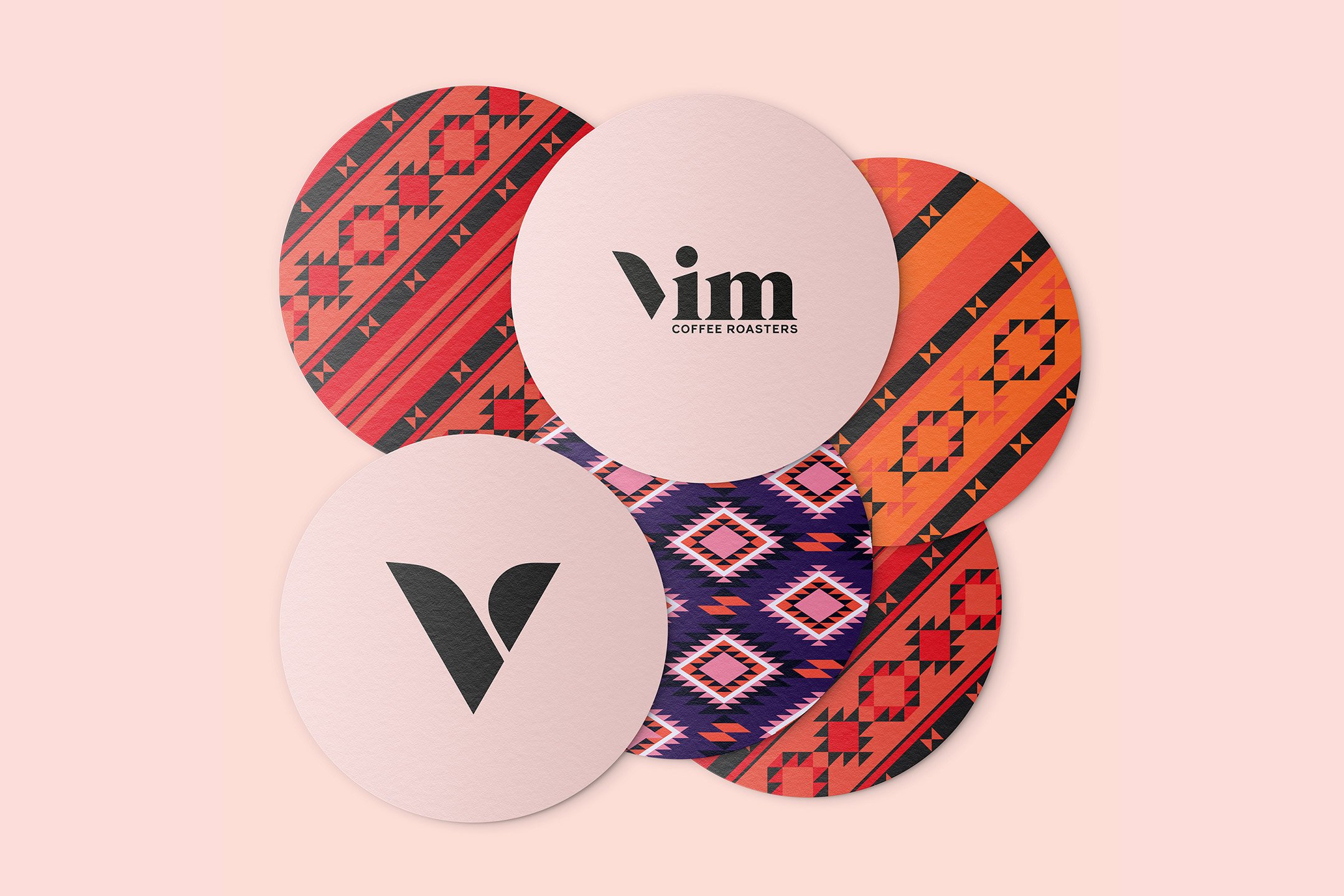 Six round coasters on a peach background; three feature bold, colourful geometric patterns, while three are light pink—one with "Vim Coffee Roasters," one with a black "V," and one blank. Perfect for a strategically‑led branding studio or start-ups seeking scalable growth strategies.