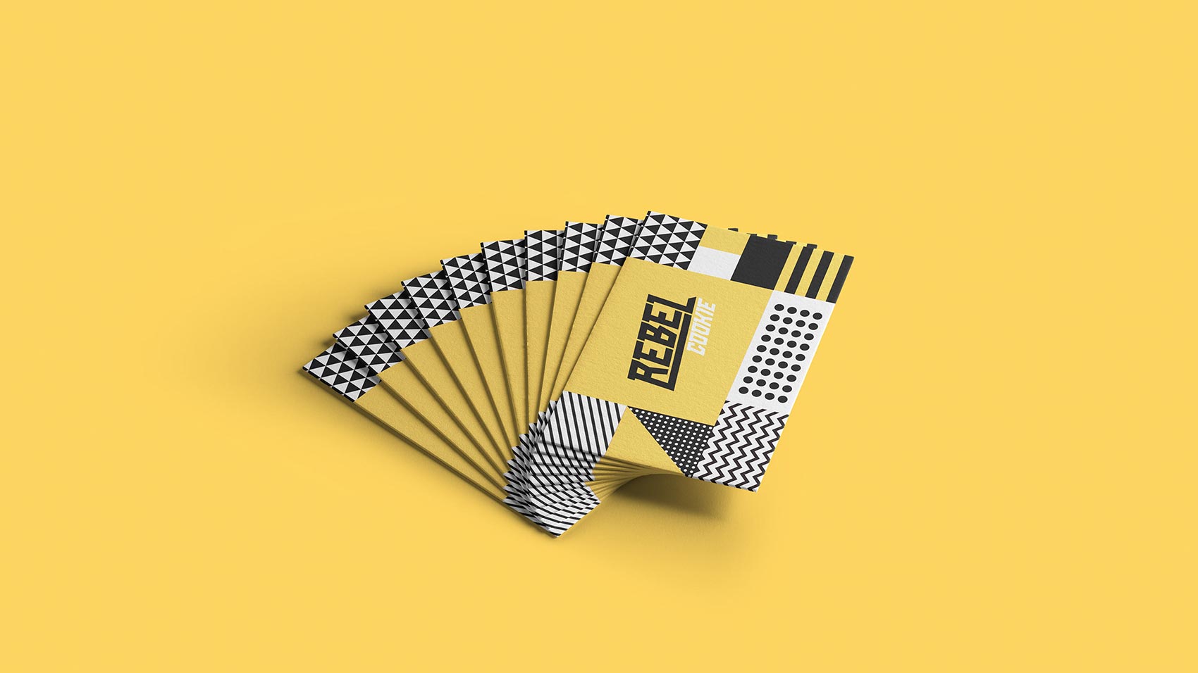 A fan of business cards with bold black, white, and yellow geometric patterns sits on a solid yellow background. Perfect for a strategically‑led branding studio focused on scalable growth strategies for start‑ups, each card features “REBEL ONLINE” in a modern font.