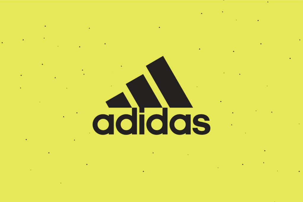 The Adidas logo, featuring three black diagonal stripes and bold lowercase lettering, is centred on a bright yellow background with scattered black dots—a creative that converts ideally for scalable growth strategies for start-ups.